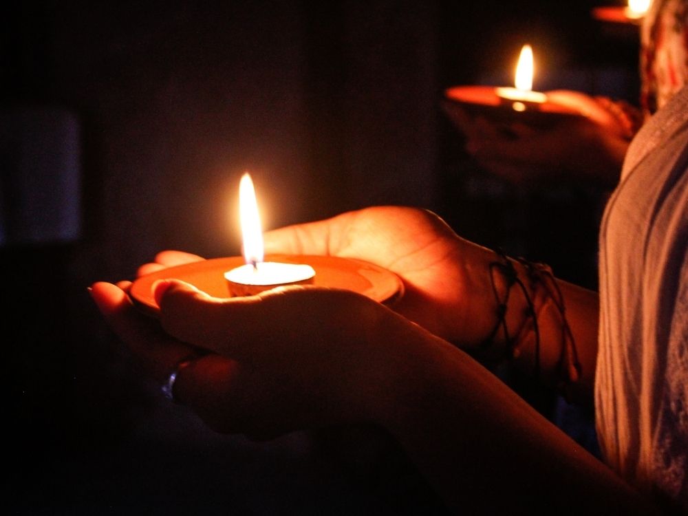 Espiritualidade na Meia-Idade: Encontre o Seu Caminho, imagens das mãos de pessoas segurando velas acessa no lugra escuro